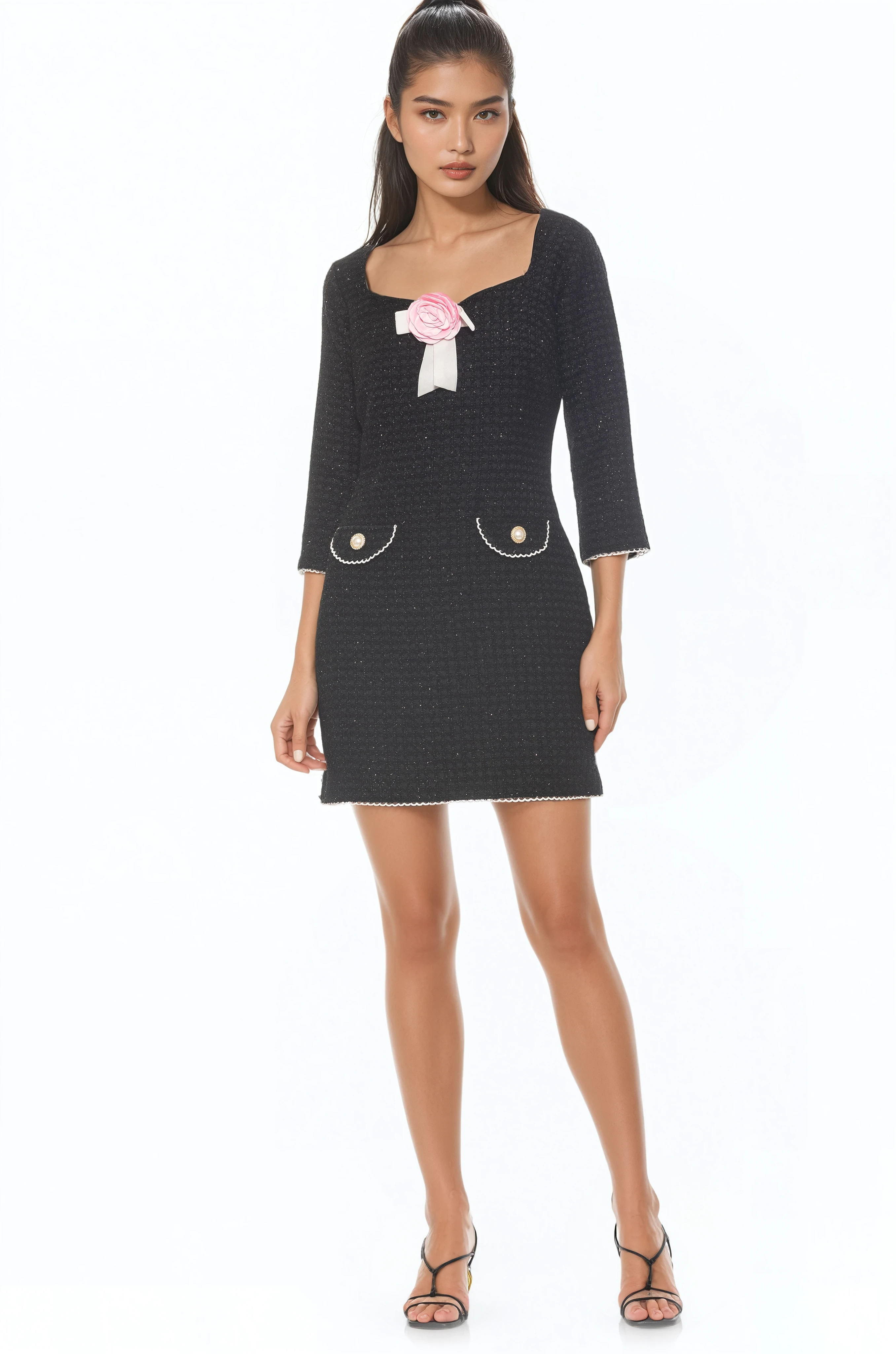 Front view black mini dress, 3/4 sleeve, princess neckline, front pockets with gold trim, rose at neck.