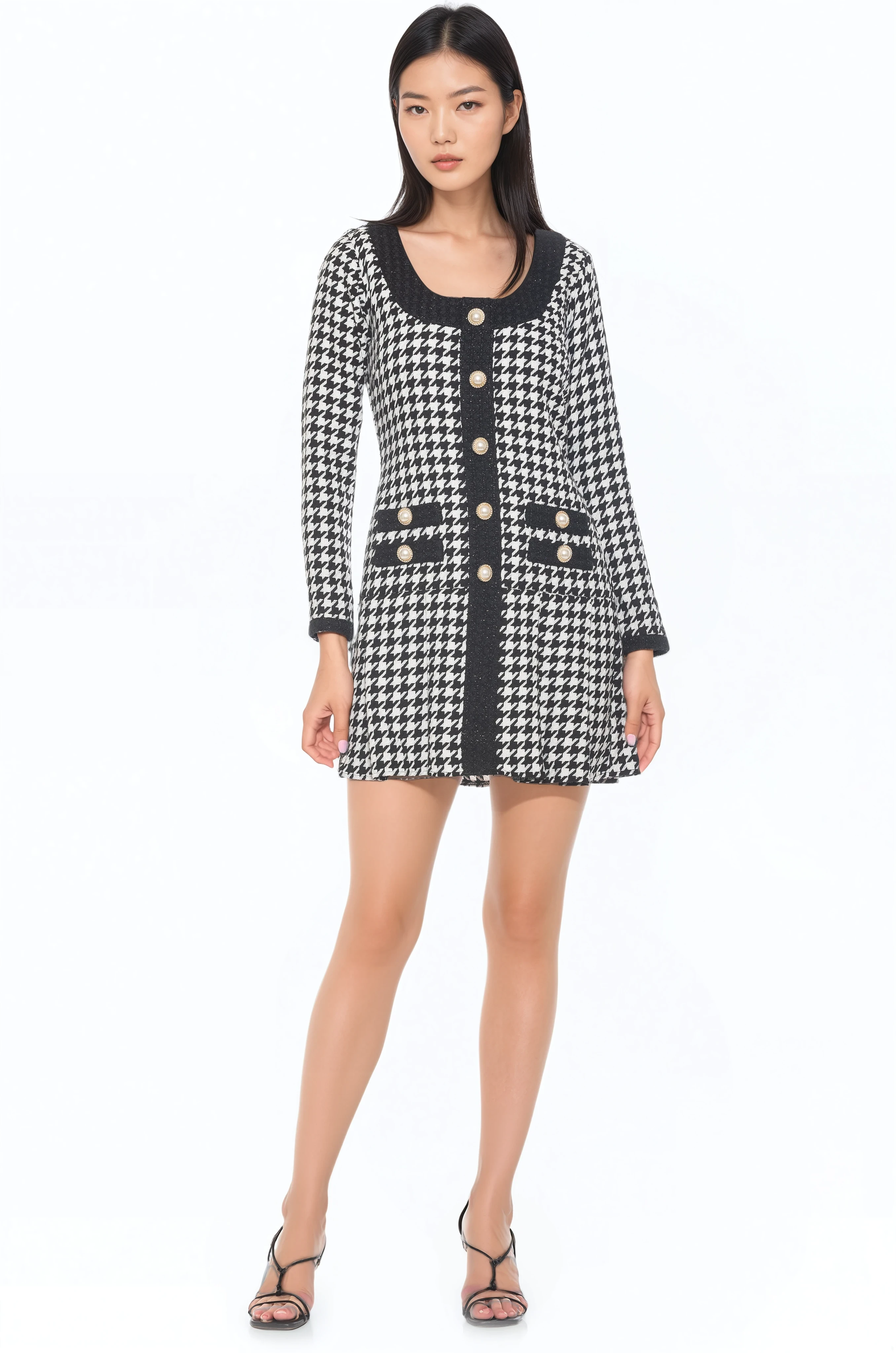 Front view black and white houndstooth mini dress, scoop neck, contrast black detail, gold rim pearl buttons, drop waist and pleated skirt.