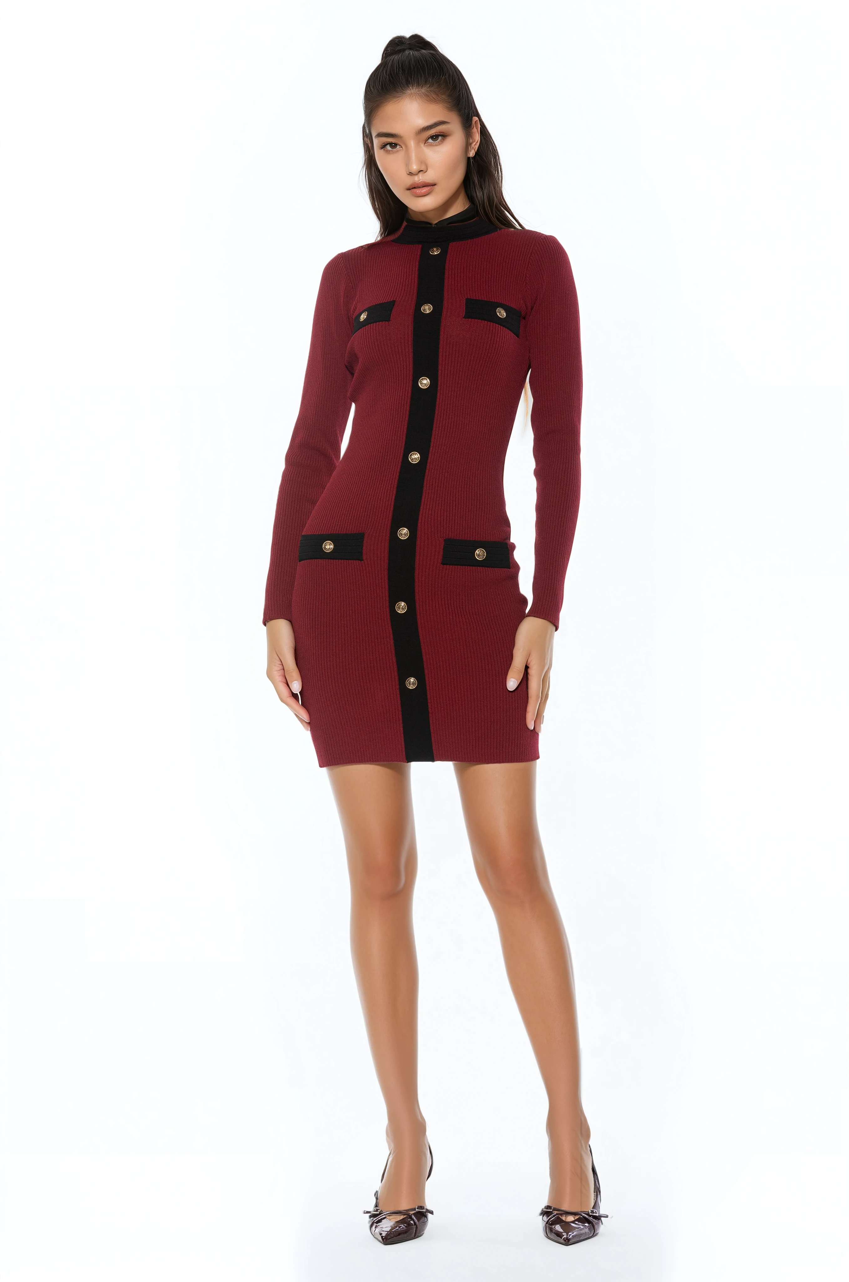 Front view burgundy long sleeve knit mini dress, crew neck with black contrast detail and mock gold snap buttons.
