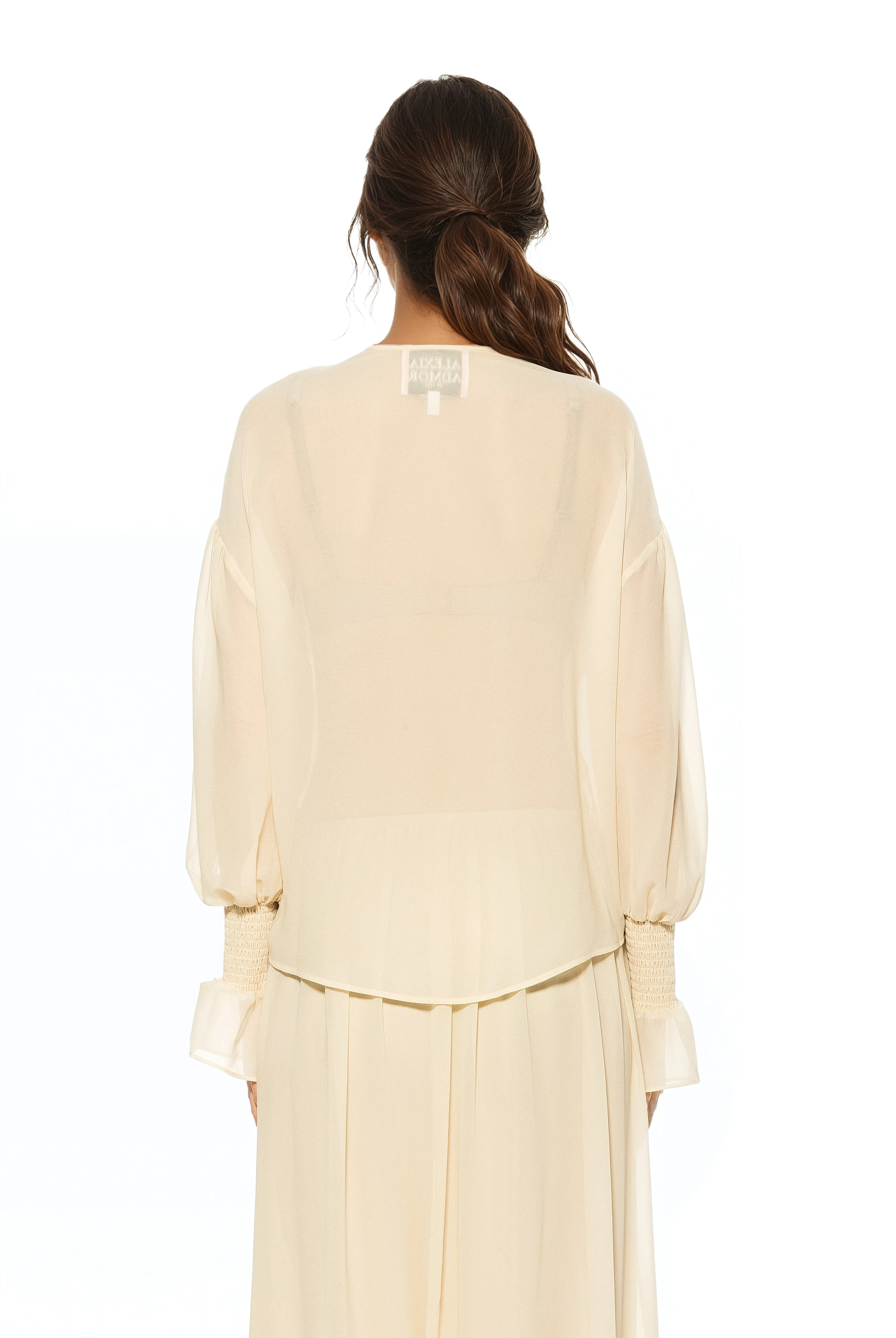 Back view ivory ruffle blouse, shirt tail hem, blouson sleeve with smocked ruffle cuff.