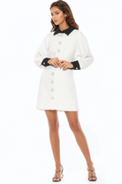 Front view ivory tweed mini dress, long sleeves, contrast black collar and cuffs, gold rimmed ivory button front.