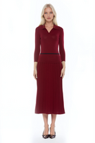 Front view burgundy knit  midi dress with drop waist, contrast black detail, pleated bottom, knit collar and 3/4 sleeves.