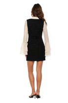 Back view black boucle vest dress, mock ivory ruffle sleeve blouse with bow at neck.