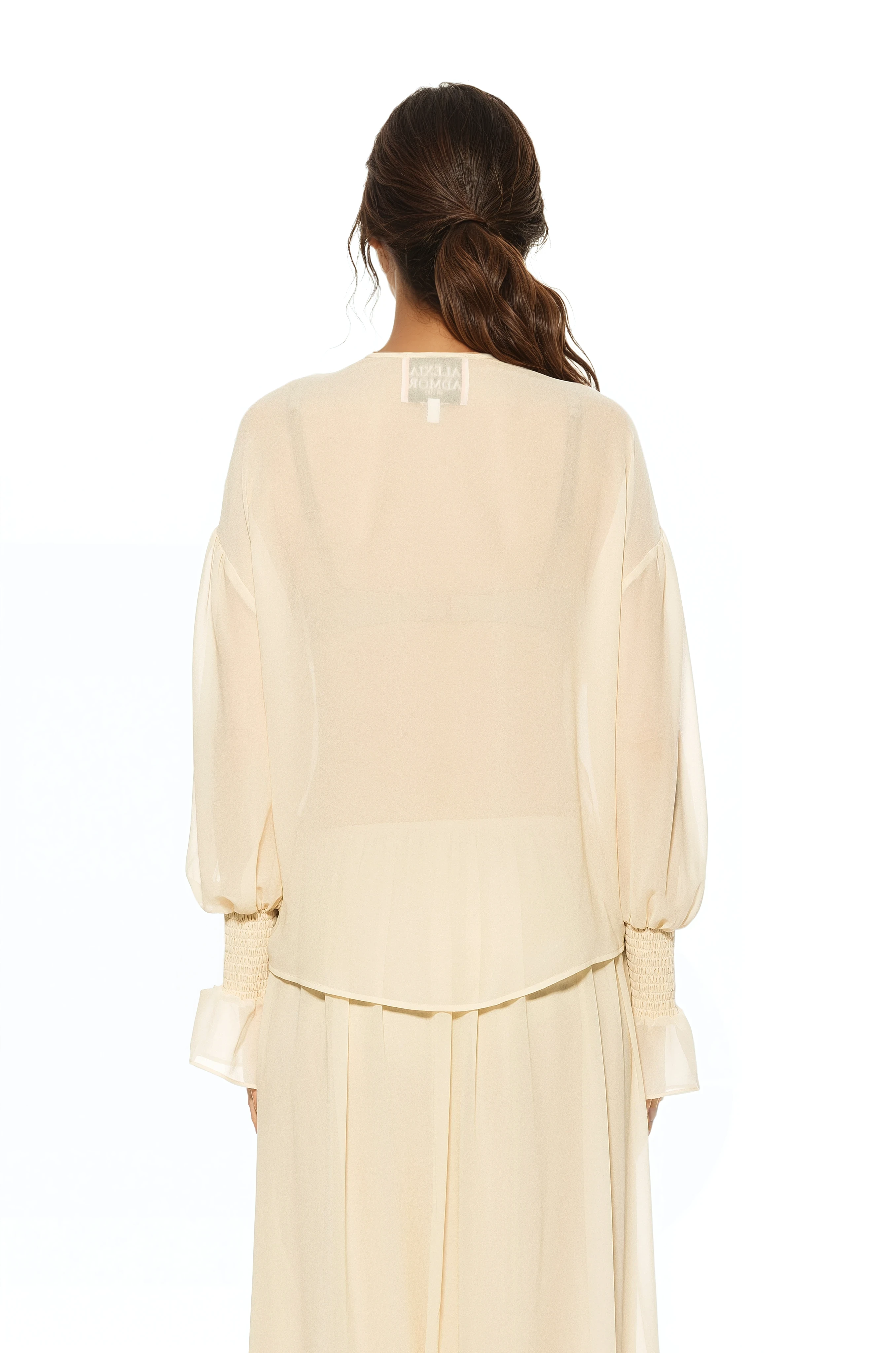 Back view ivory ruffle blouse, shirt tail hem, blouson sleeve with smocked ruffle cuff.